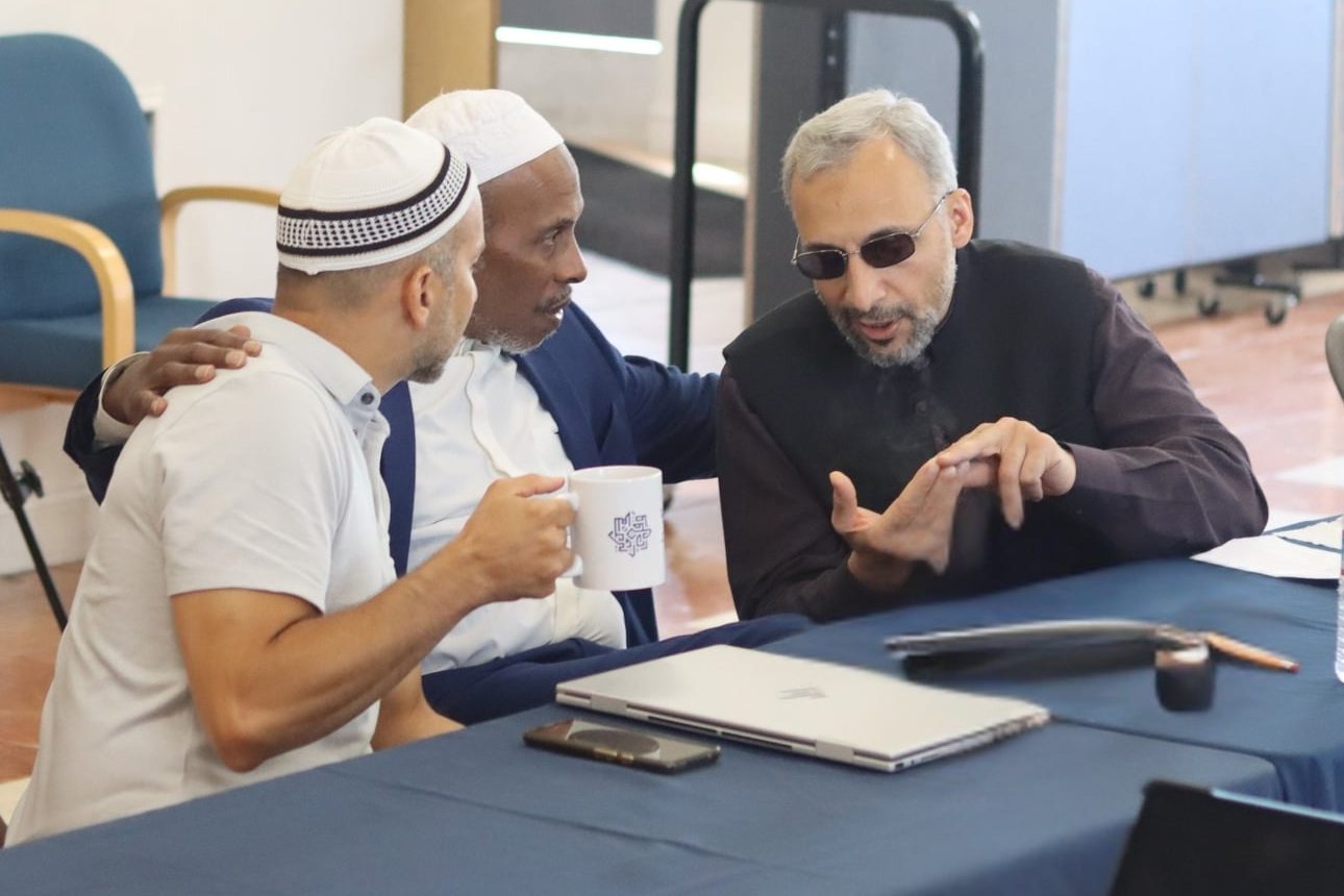 Three participants discussing together at a BIS table, one holding a BIS mug.